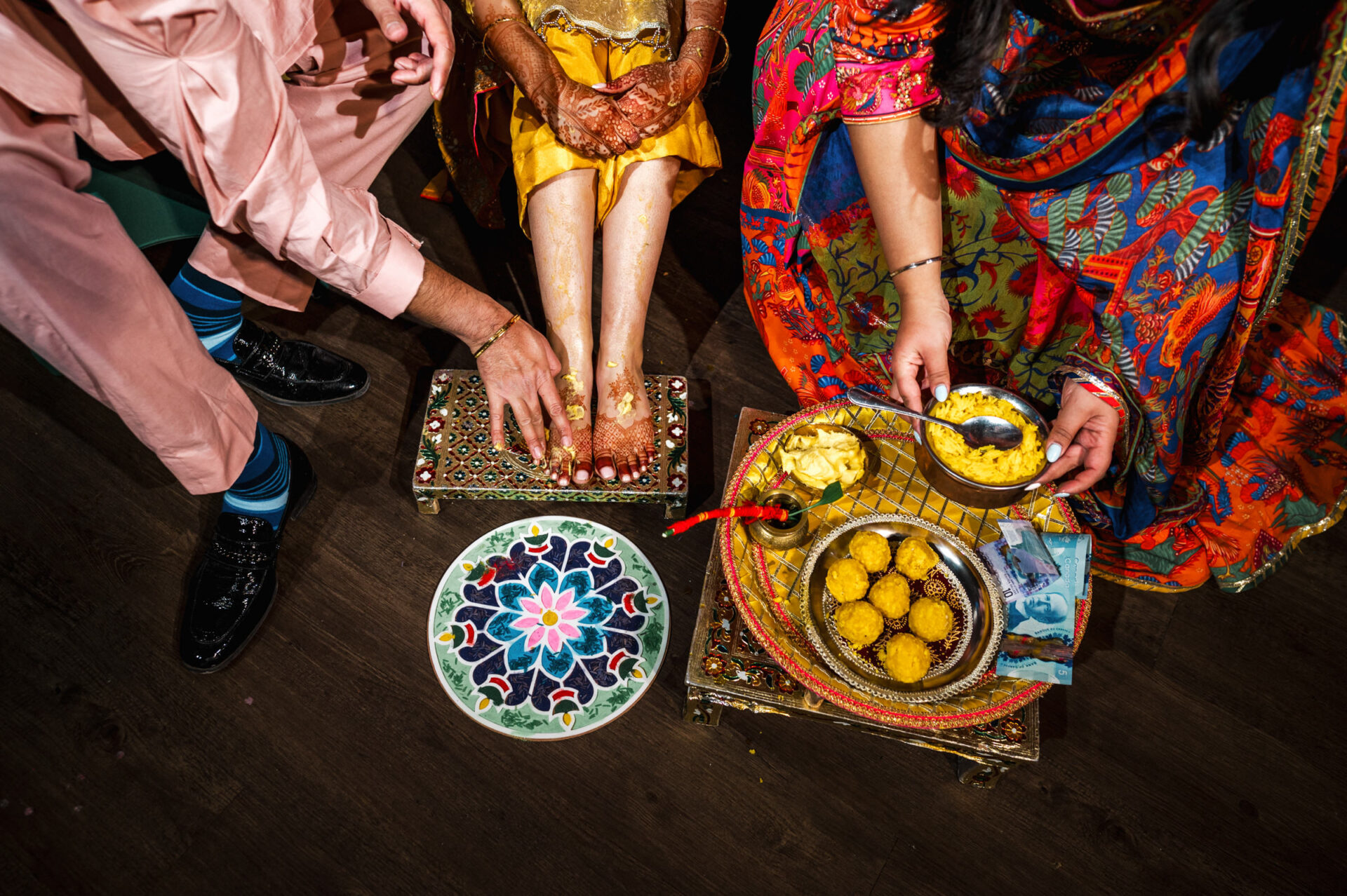 Traditional Sikh foot ritual with colorful attire and decorative trays of food and flowers.