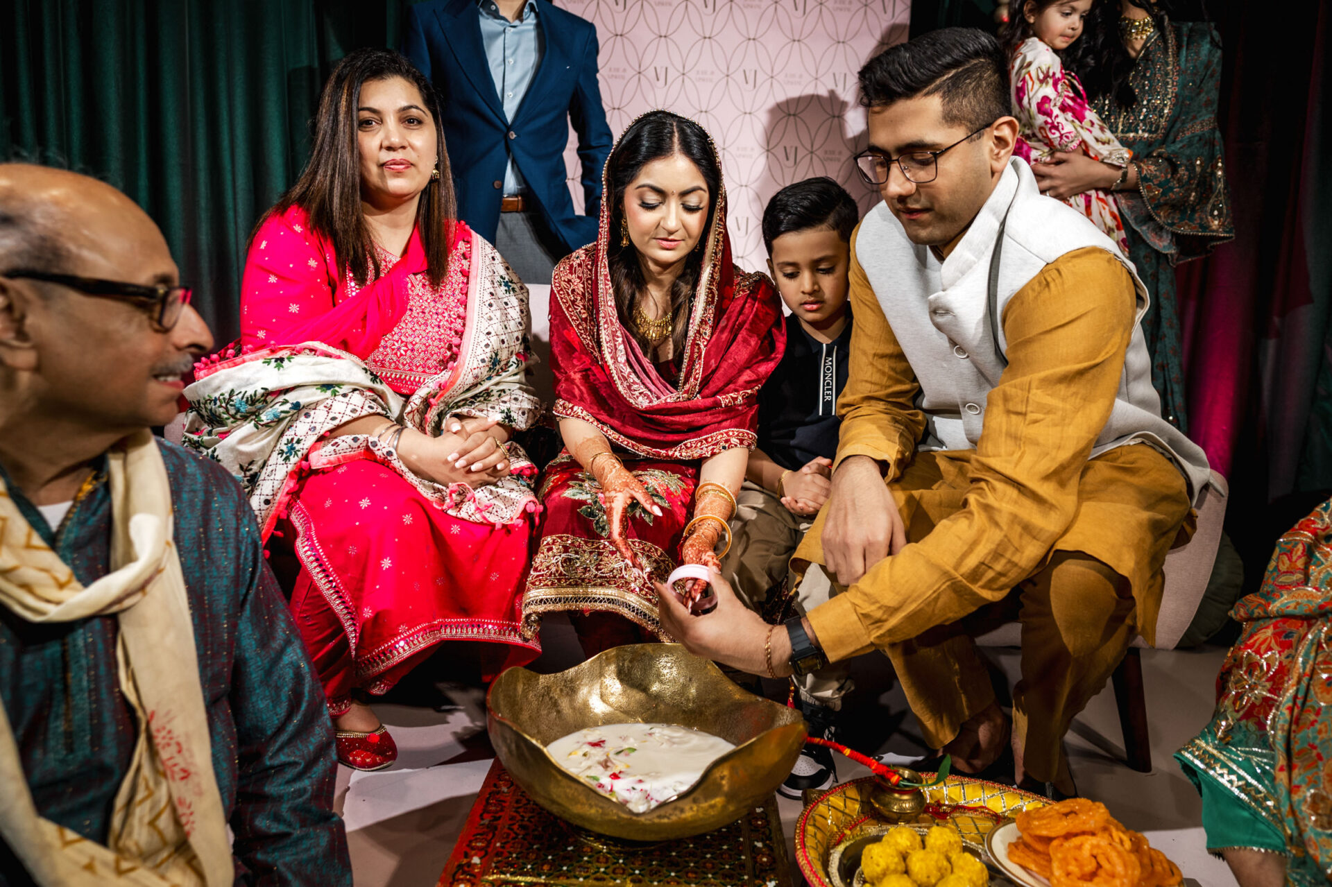 People in traditional attire at a Sikh ceremony with a large golden bowl.
