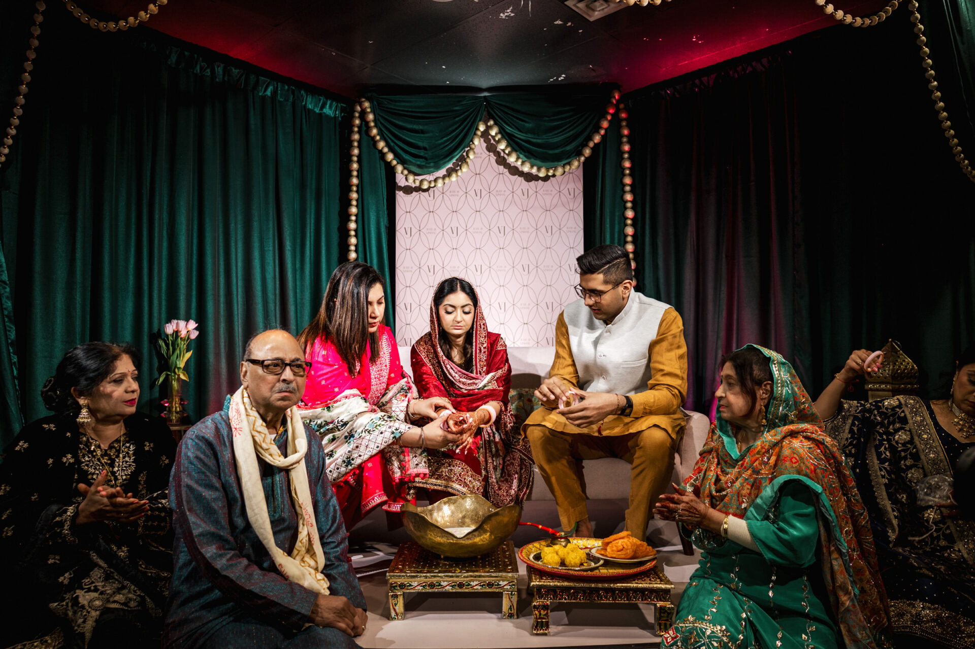 A traditional Sikh ceremony with people in colorful attire around a decorated area.