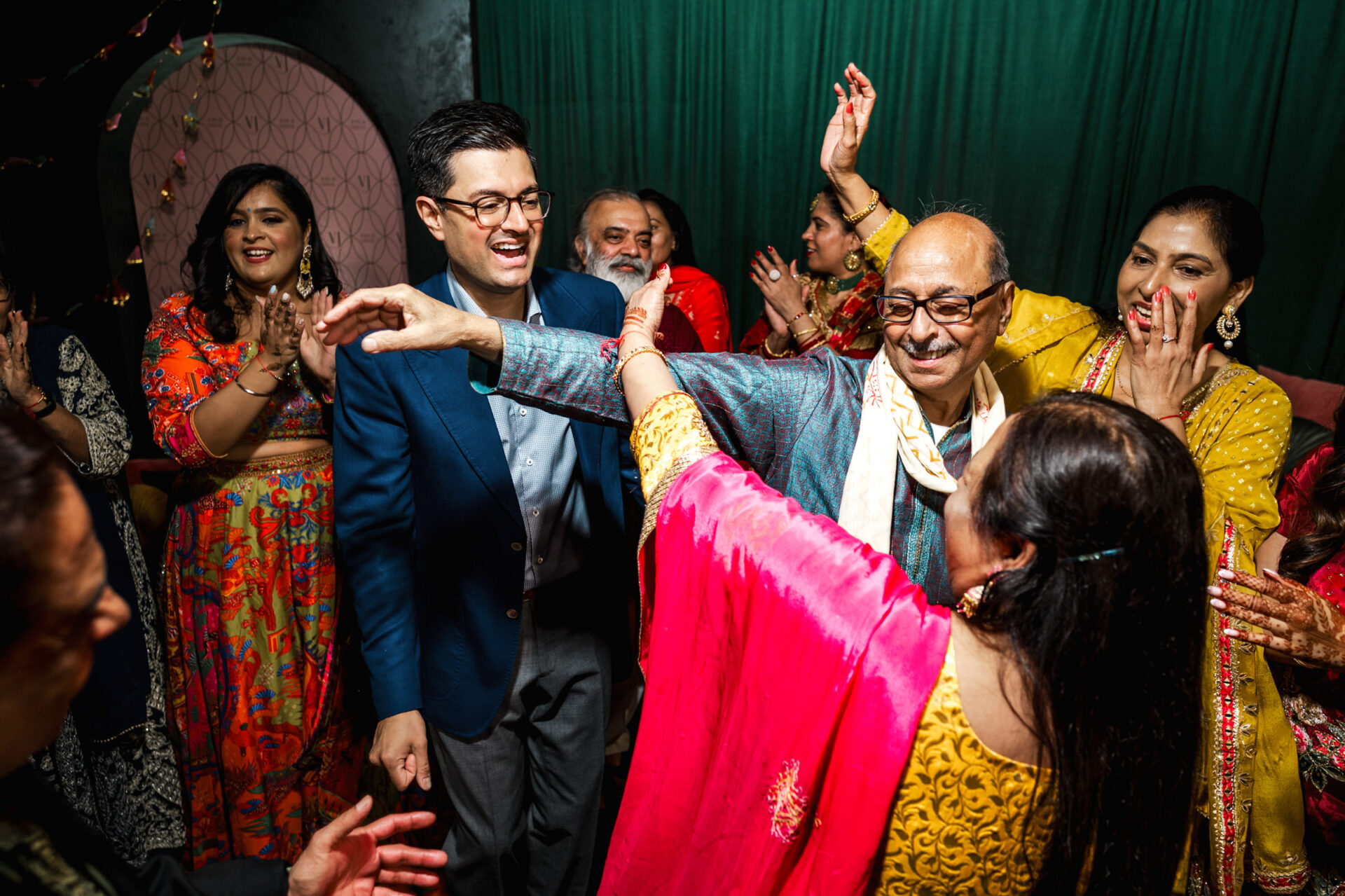 People joyfully dancing and celebrating in colorful attire at a Sikh wedding.