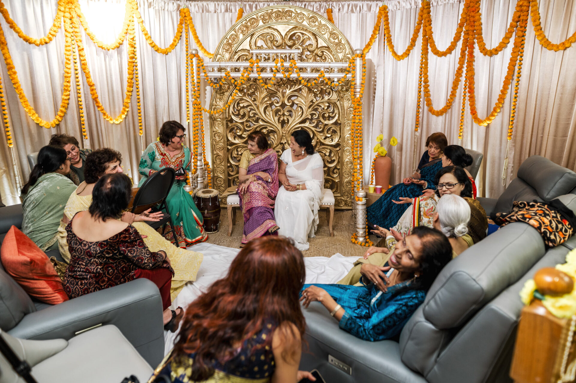 People seated at a Sikh wedding, engaging in festive conversation, wearing traditional attire.
