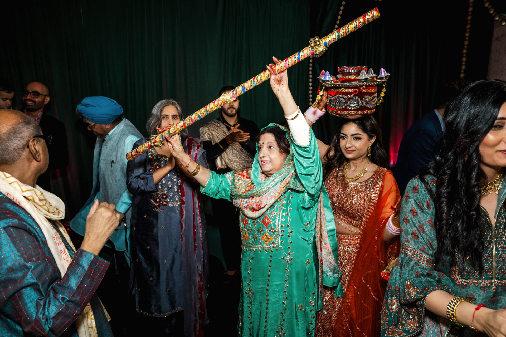 People celebrating in traditional attire and props at a vibrant Sikh wedding event.