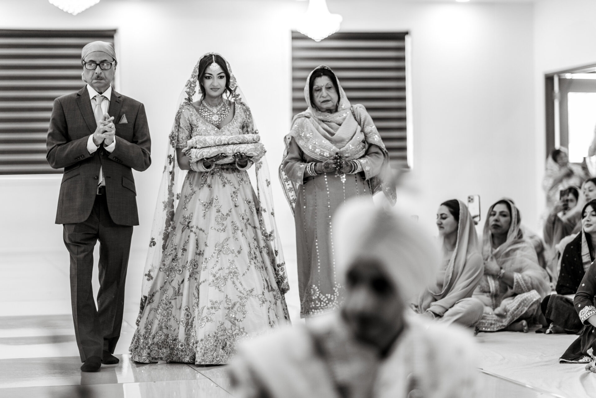 A bride walks with her parents in a traditional Sikh ceremony.