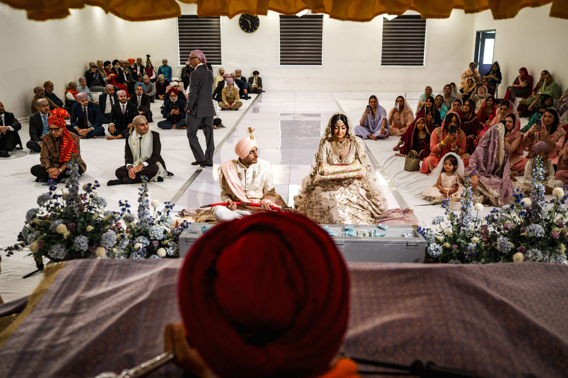 A Sikh wedding in progress, with the couple seated before a captivated audience.