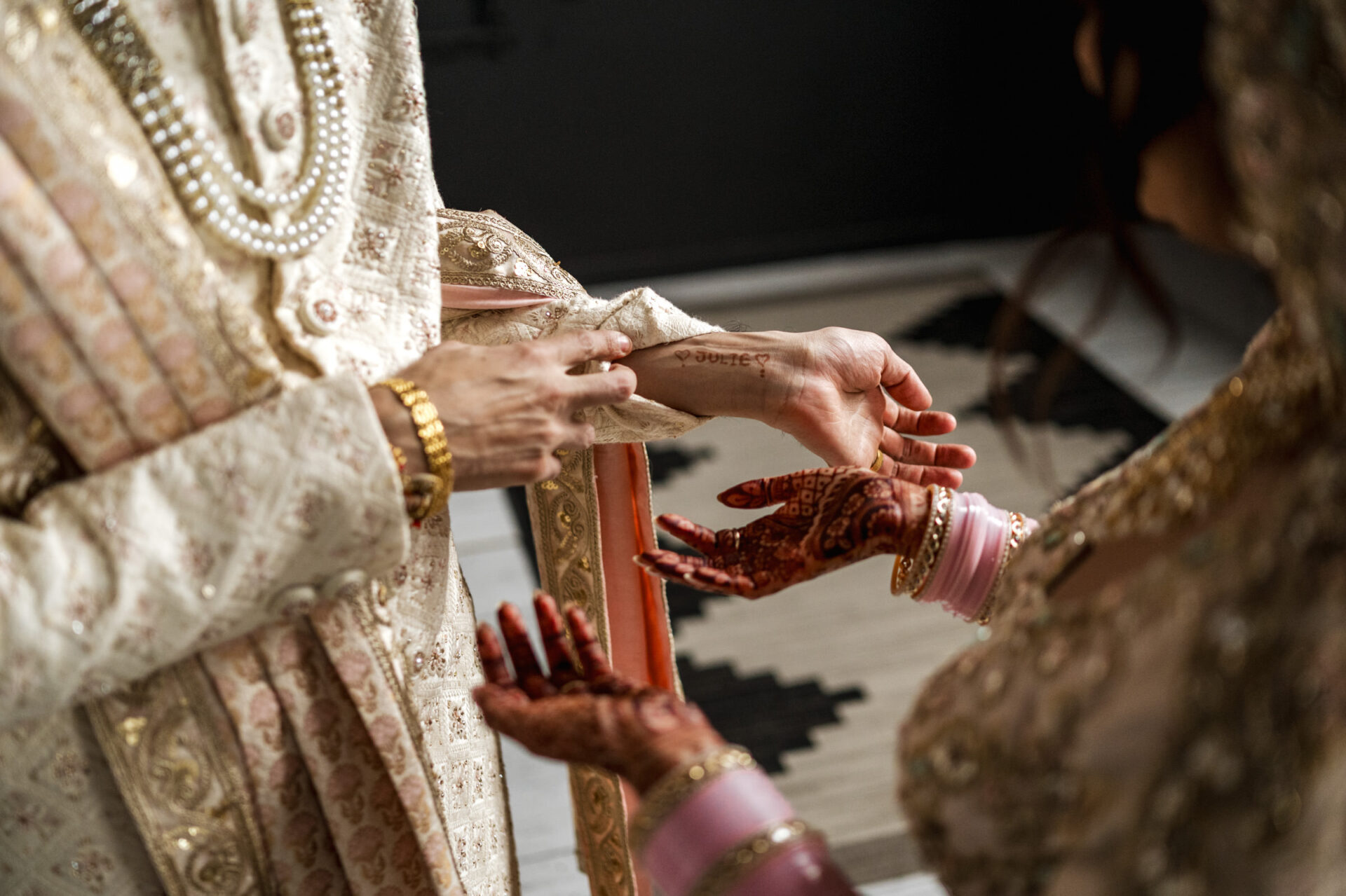 Hindu bride and groom in traditional attire, intricate henna adorns the bride's hands.