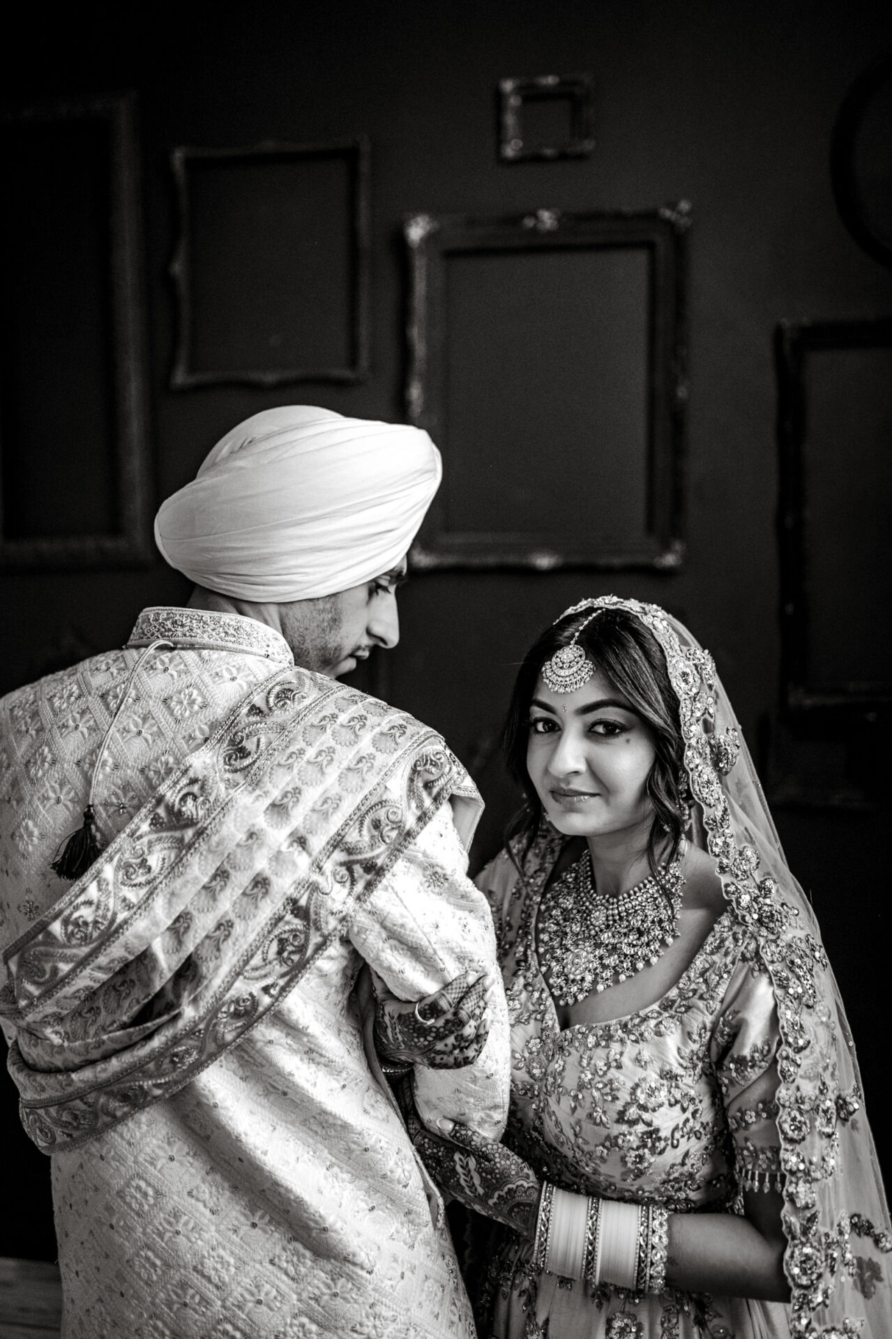 A couple in traditional Sikh wedding attire shares an intimate moment.