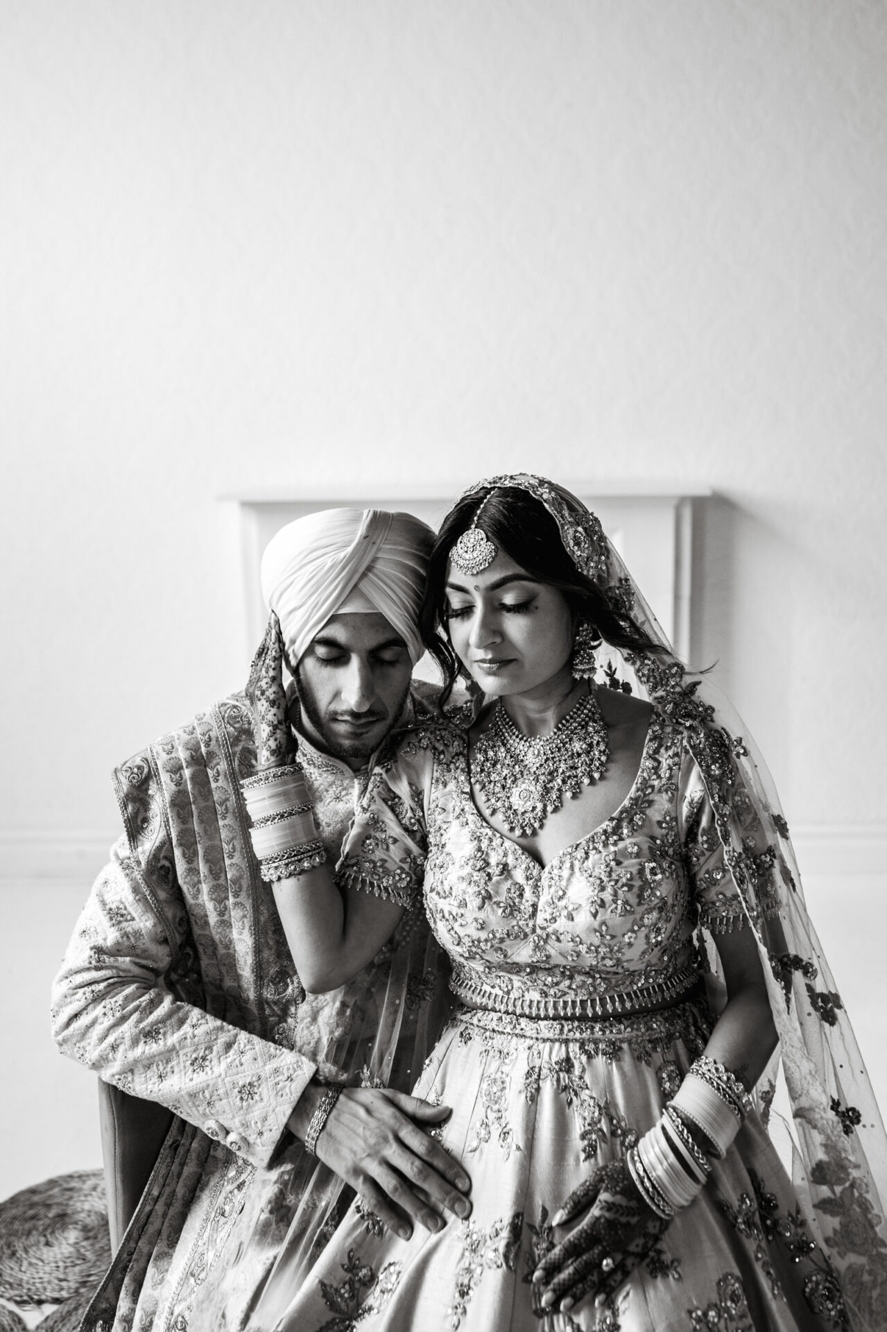 Bride and groom in traditional attire, embracing at a serene Sikh wedding.