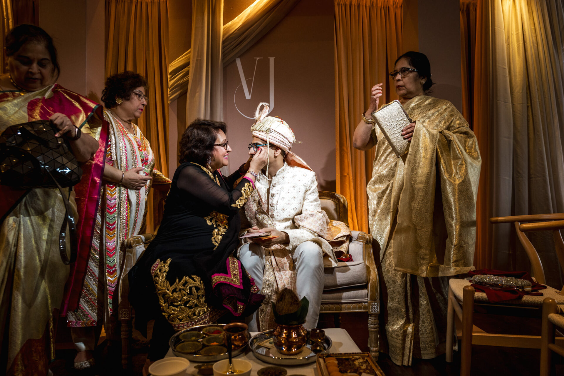 A groom in traditional attire is surrounded by family at a Sikh wedding ceremony.