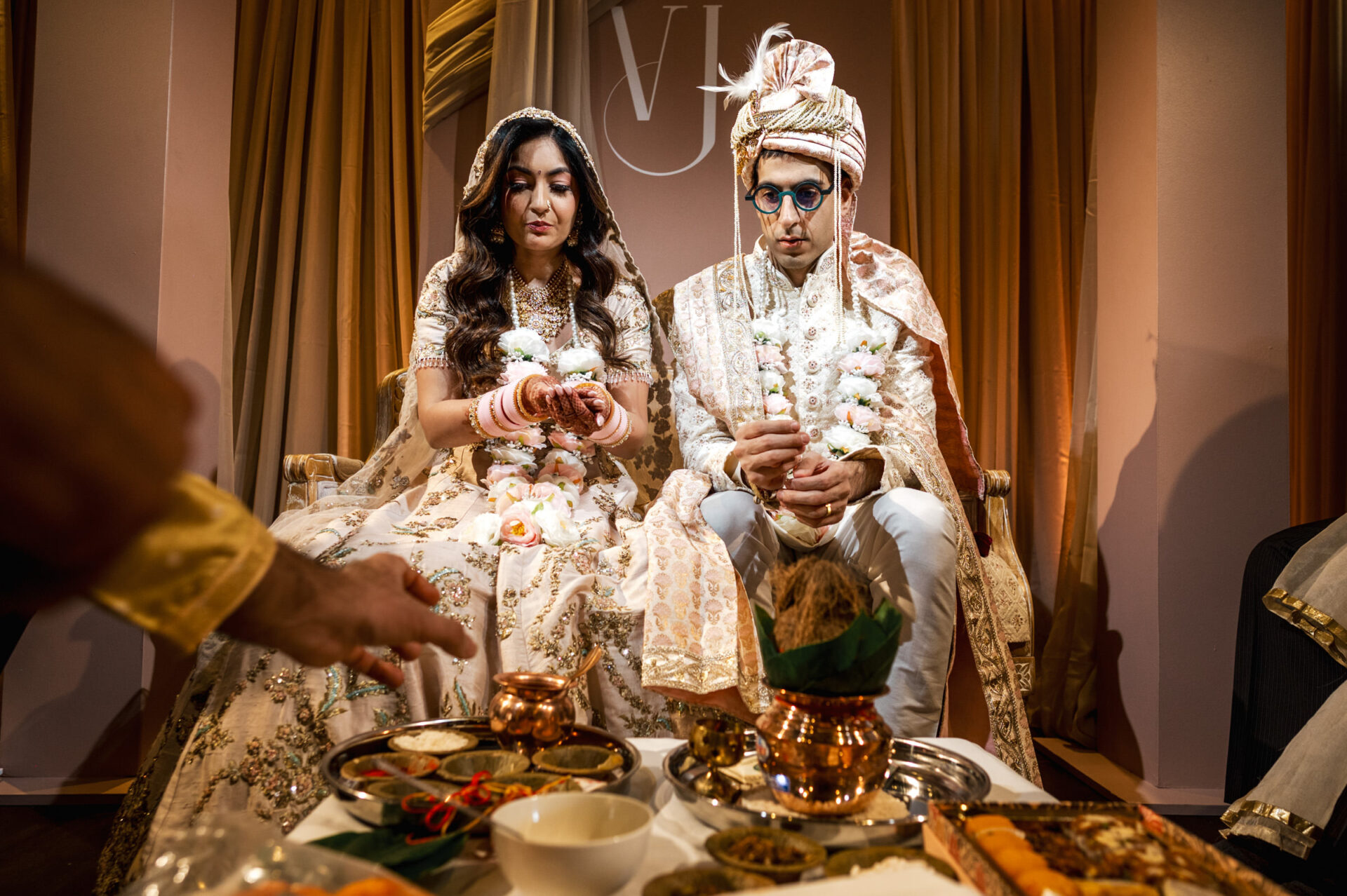 Sikh bride and groom in traditional attire during a wedding with ceremonial items.