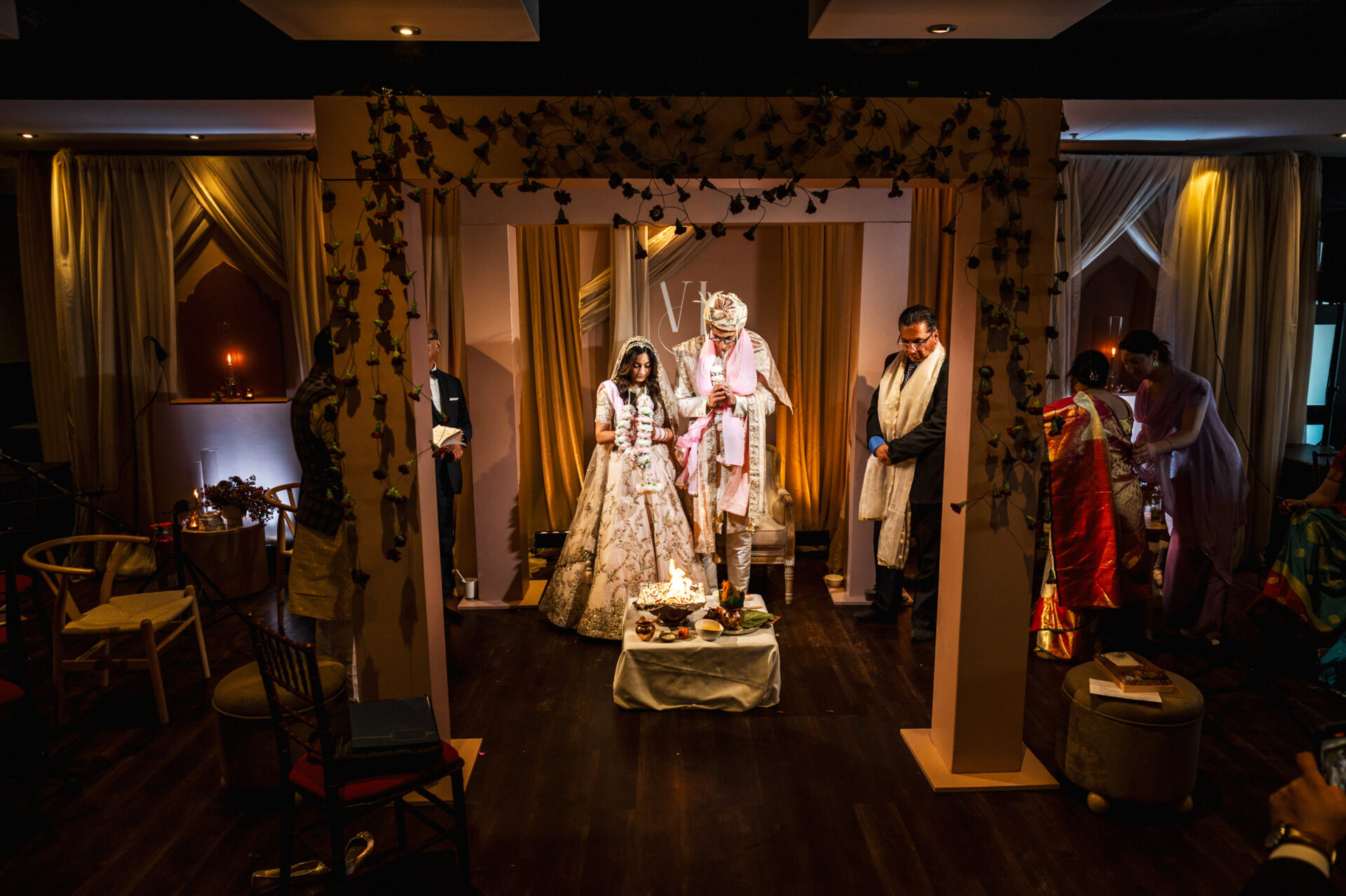 Bride and groom stand under a decorated arch at their Sikh wedding ceremony.