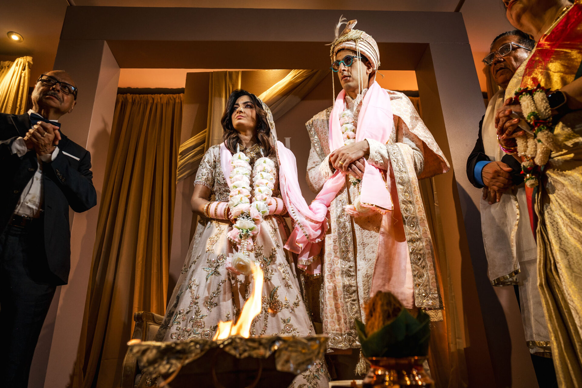 Bride and groom in traditional attire at a Sikh wedding, with guests in the background.