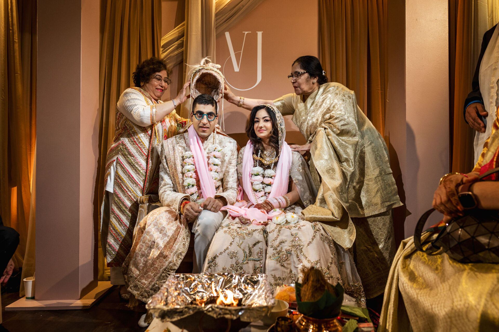 Bride and groom in traditional attire during a Sikh ceremony with elders blessing them.